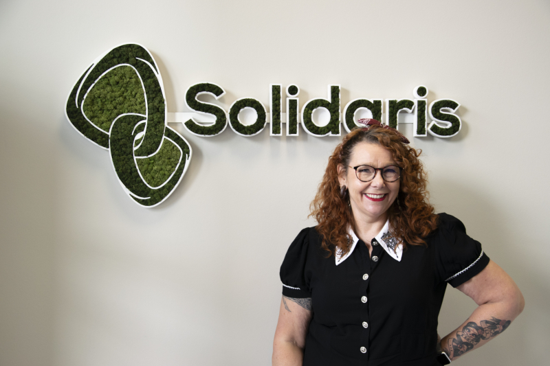 Vrouw poseert naast het Solidaris logo